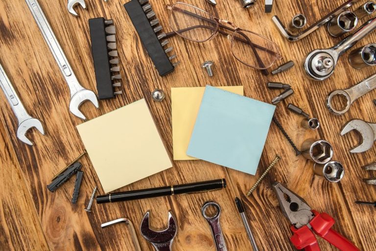 A wooden table displaying various tools, including wrenches and a notepad, arranged neatly for a DIY project.
